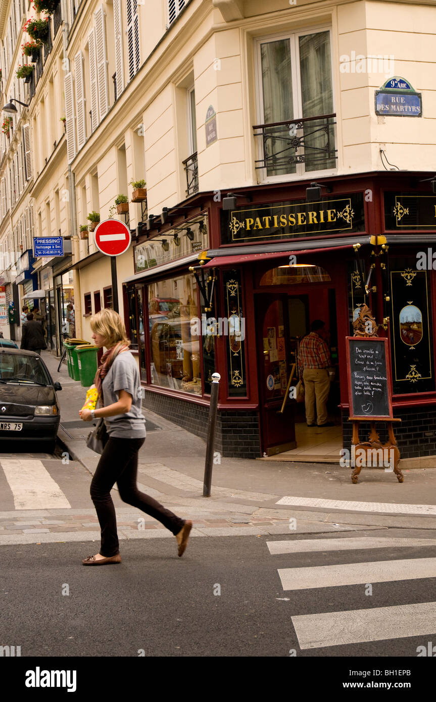 Ragazza camminare passato una pasticceria a Parigi Francia Foto Stock