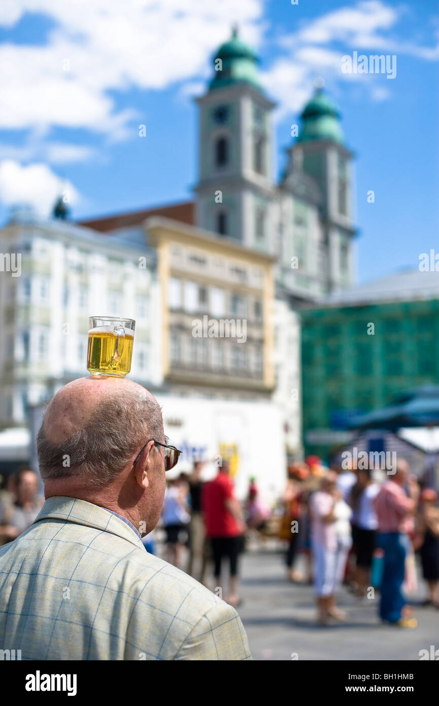 L'uomo il bilanciamento di un boccale di birra sulla sua testa, a cupola in background, la piazza centrale di Linz, Austria superiore, Austria Foto Stock