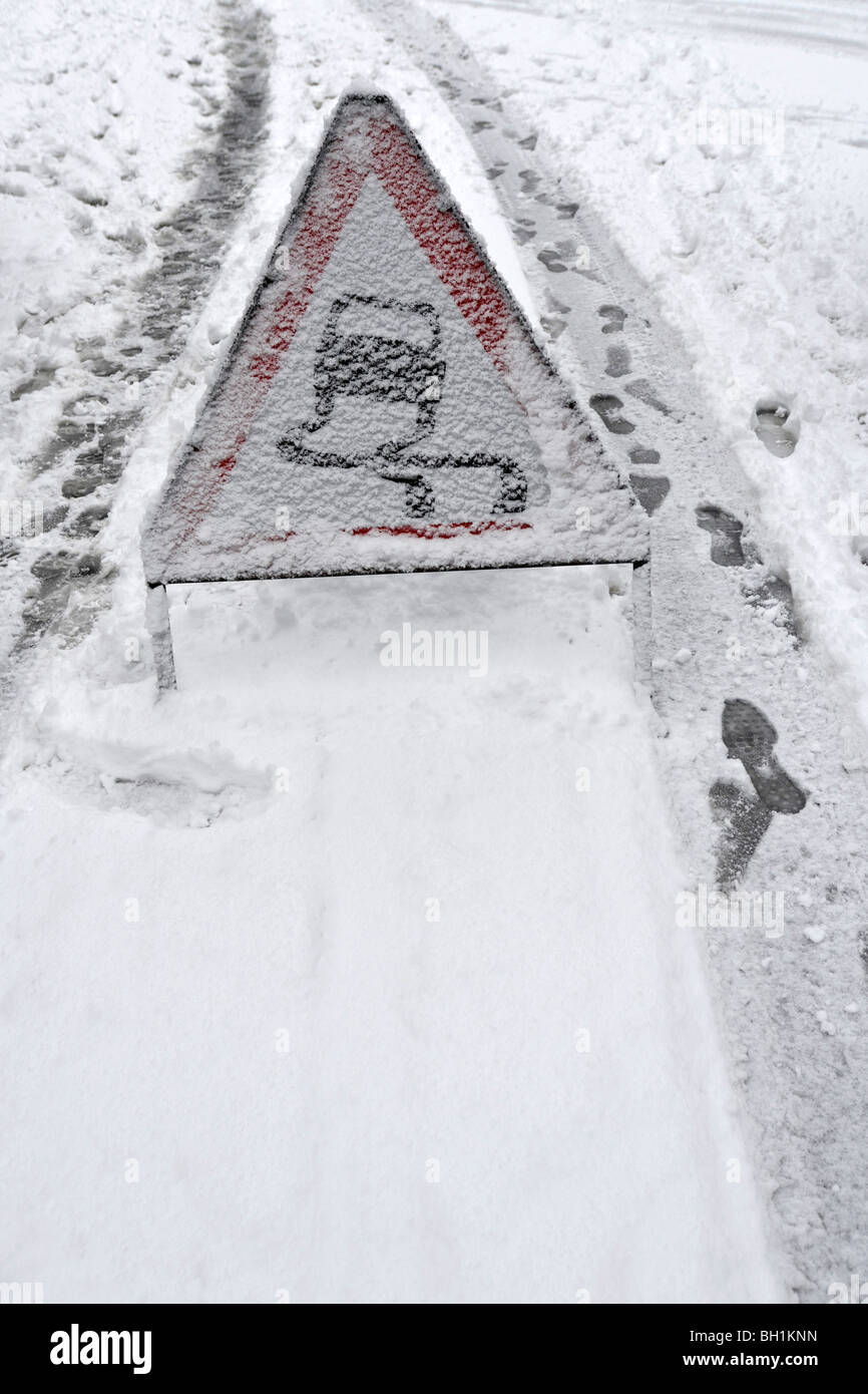 Segno di pericolo in allarme neve di slittamento su strada Foto Stock