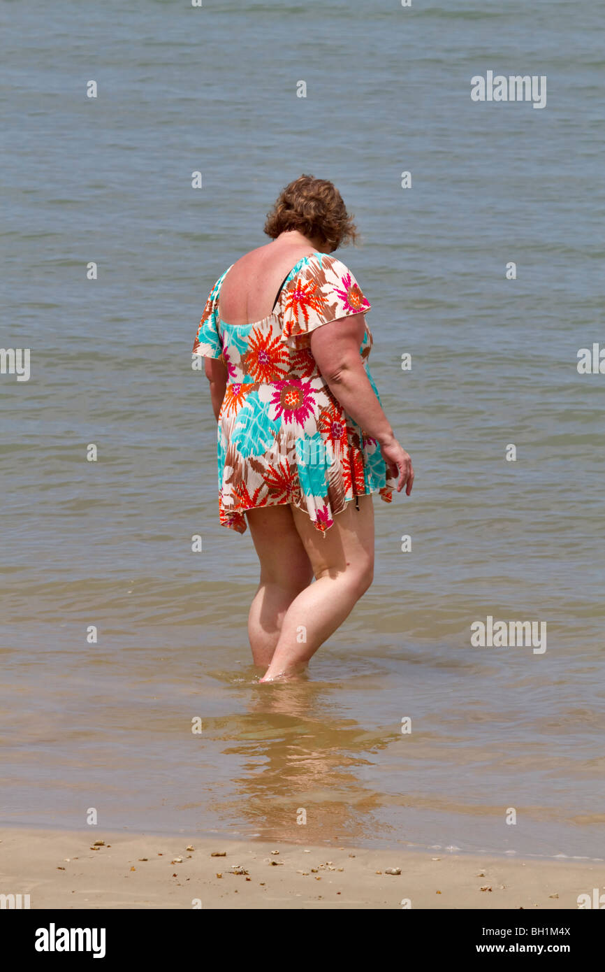 Grande donna wading in spiaggia Foto Stock