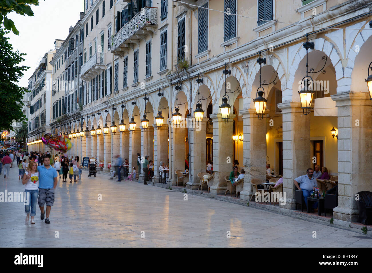 La gente a piedi attraverso la città e seduta in caffè sotto i portici di Liston, Corfu, Isole Ionie, Grecia Foto Stock