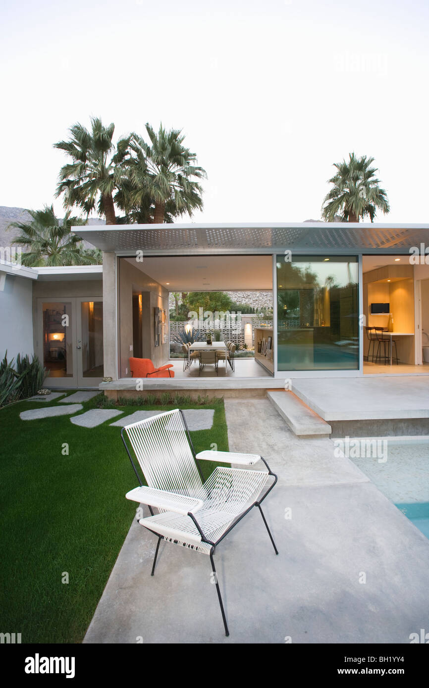 Sedia vuota sul selciato poolside area di Palm Springs home Foto Stock
