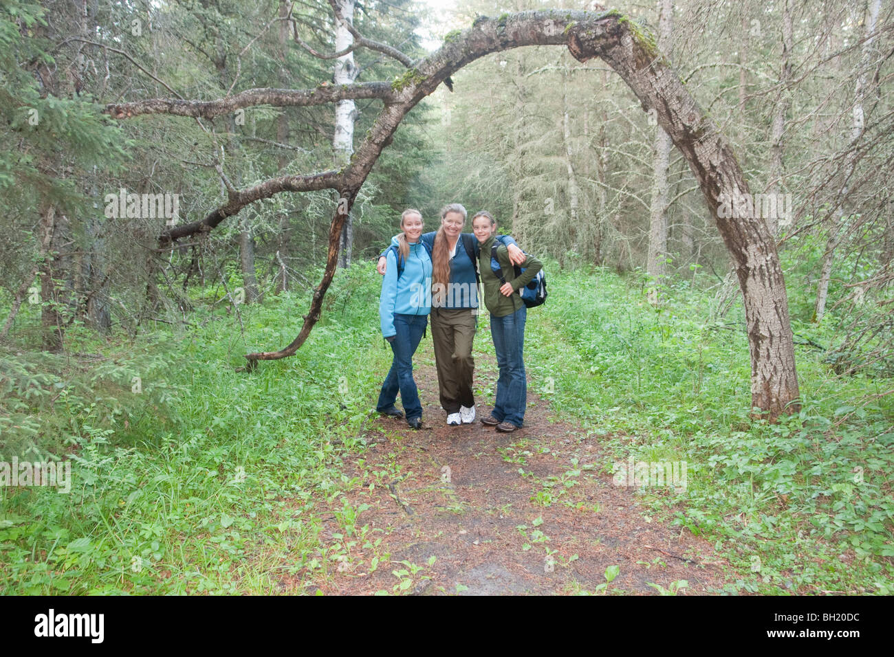 Donna e due ragazze su sentiero escursionistico accanto ad arco ad albero su sentiero, Manitoba, Canada Foto Stock