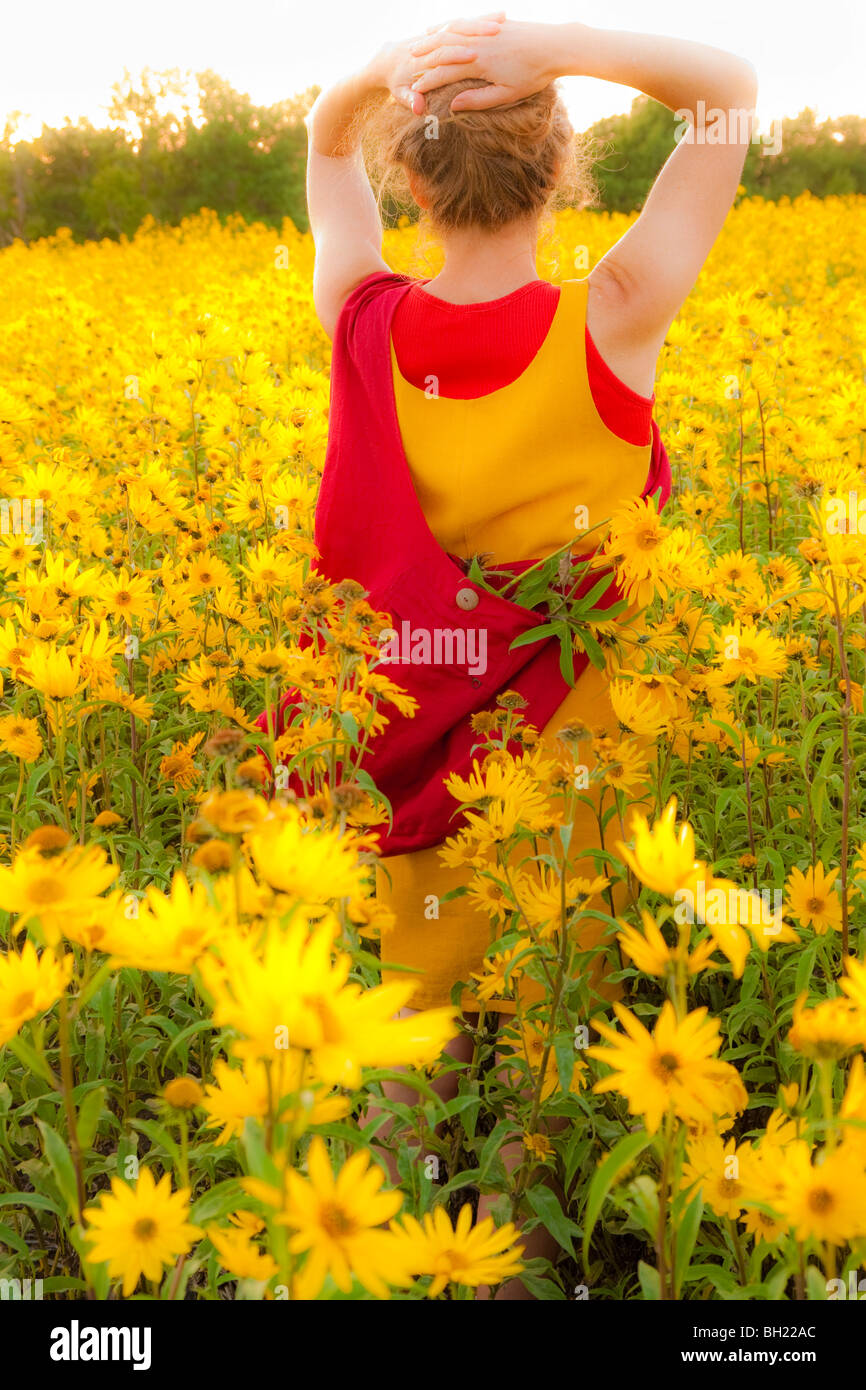 Vista posteriore della donna in piedi in un campo di fiori gialli, Manitoba, Canada Foto Stock