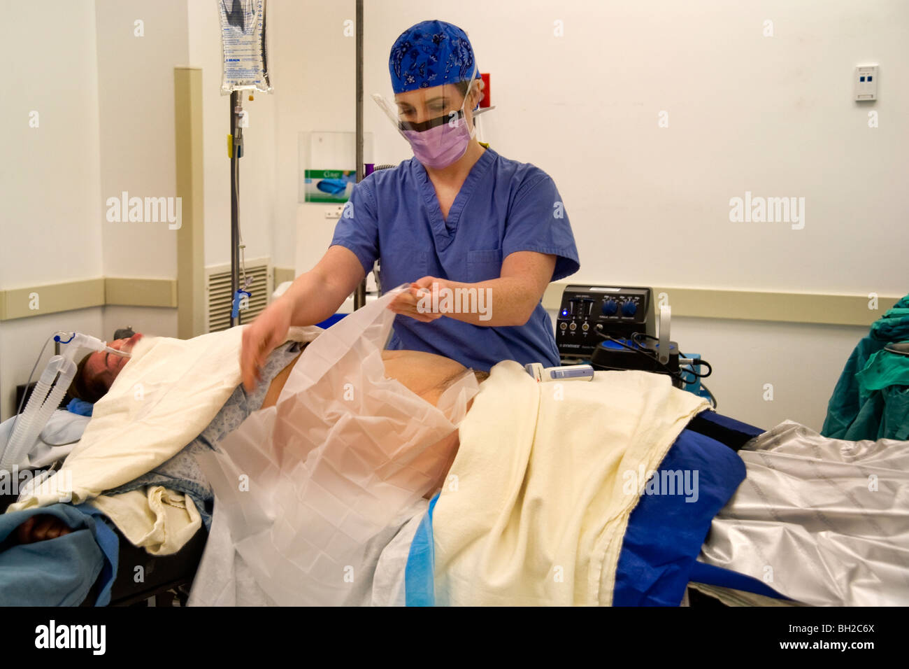 Vestito in 'scrubs' e indossare una mascherina chirurgica, una donna  chirurgo prepara il suo paziente anestetizzato in una sala operatoria Foto  stock - Alamy