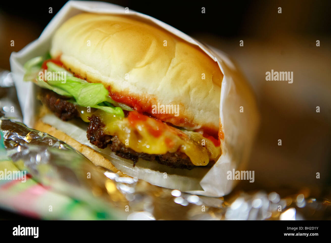 Tipico New York cheese burger, conosciuto anche come hamburger con formaggio, patate fritte, Coke e anelli di cipolla Foto Stock