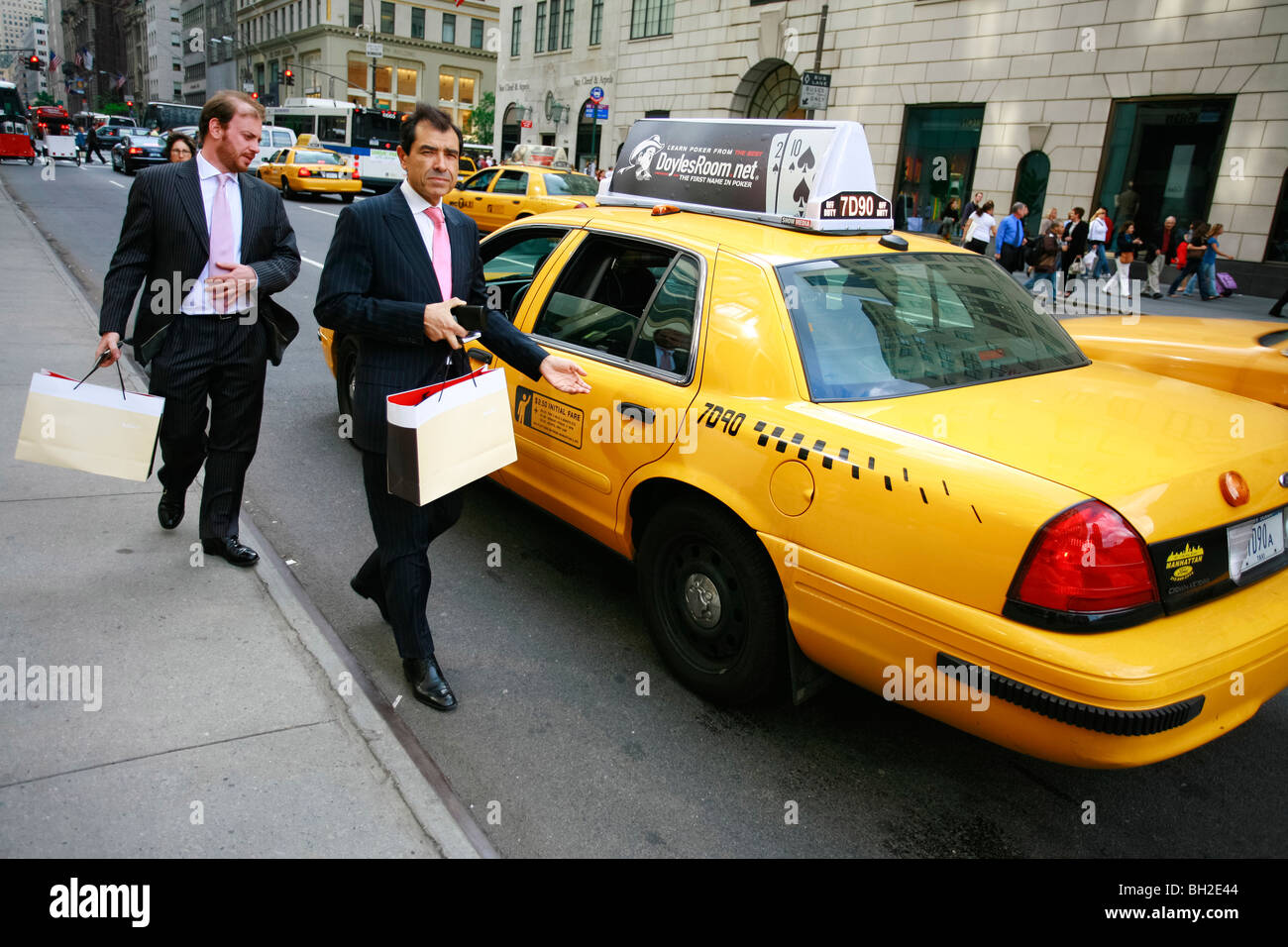 Gli uomini d' affari prendendo un taxi giallo sulla Quinta Avenue in New York Foto Stock