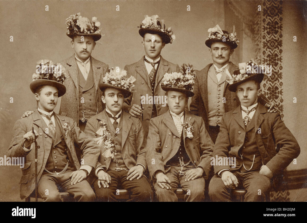 Sette uomini che indossano composizioni floreali nelle loro cappelli Foto Stock