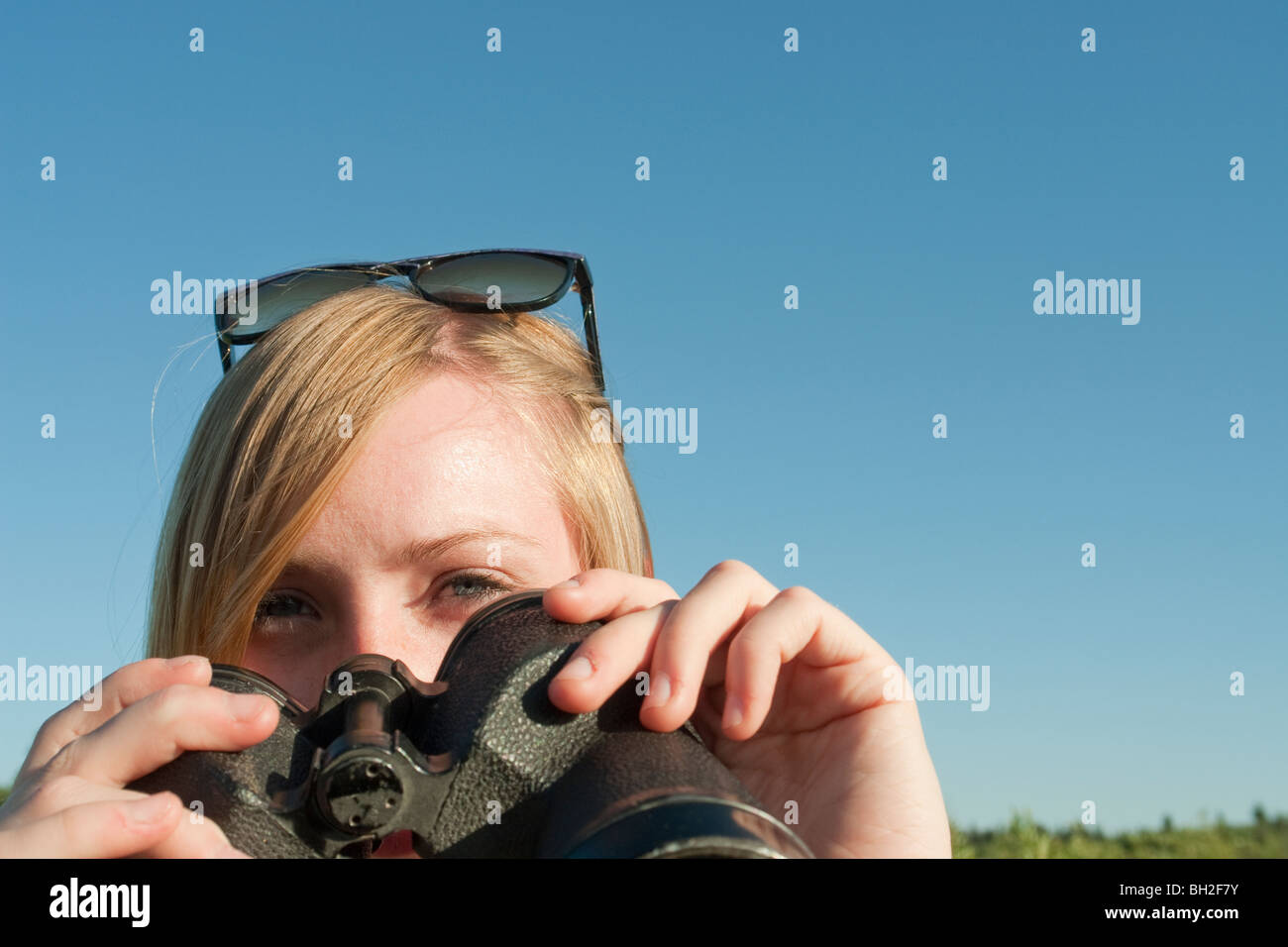 Teen girl cerca attraverso il binocolo verso la telecamera, Equitazione Mountain National Park, Manitoba, Canada Foto Stock