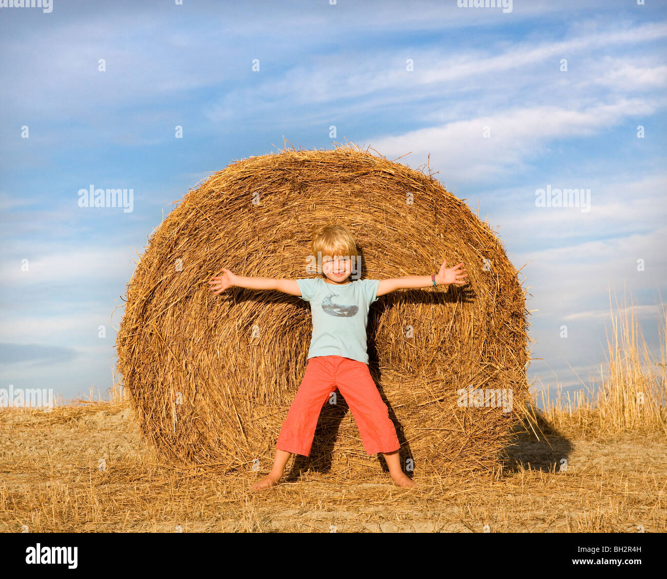 Ragazzo in piedi nella parte anteriore della balla di fieno Foto Stock