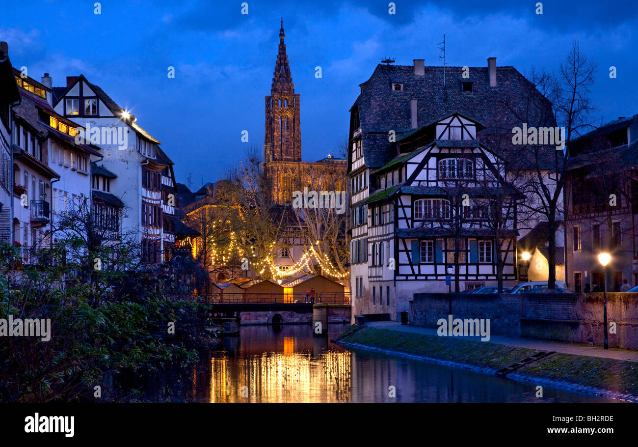 Vista del canal di vecchi edifici nel quartiere Petite France con la cattedrale di Strasburgo in distanza di notte, Francia. Foto Stock