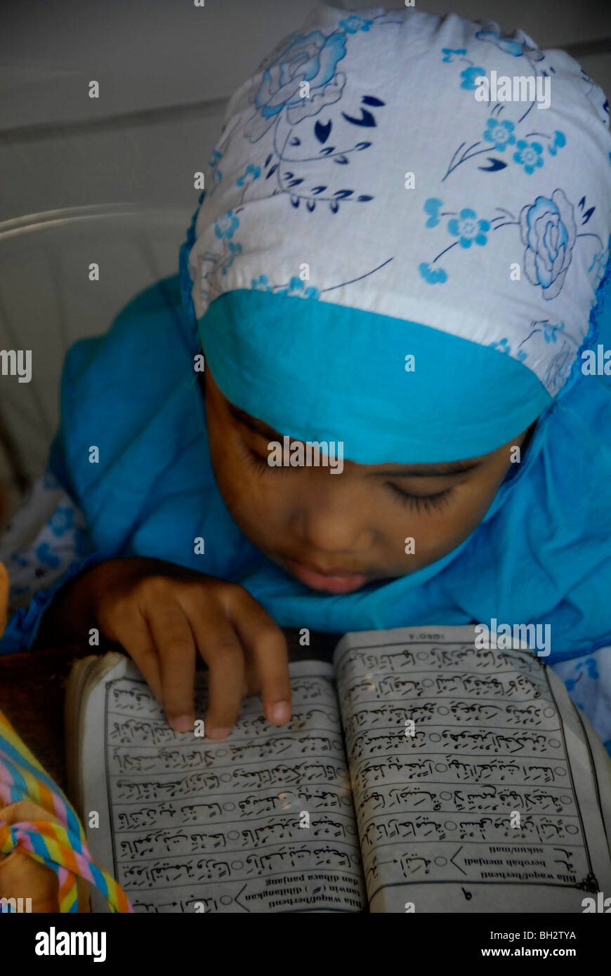 Ragazzina musulmana è la lettura Al-Quran (Corano) prenota,Kuta Bali, Indonesia. Foto Stock