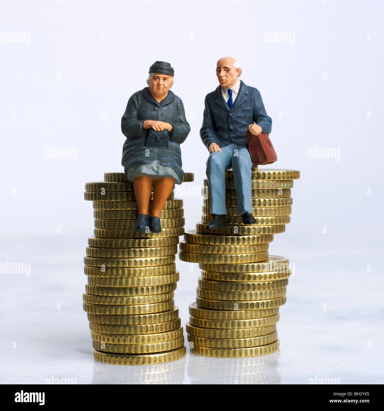 Anziani / coppie (figurine) - seduti su un mucchio di monete - risparmio / risparmio / bollette / finanziario / investimenti / pensioni Foto Stock