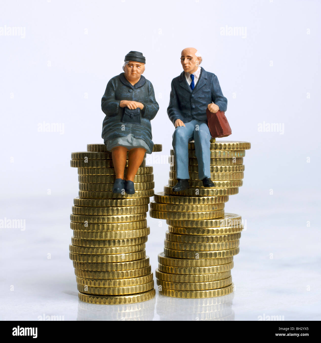 Le persone anziane / giovane (figurine) - seduta su un mucchio di soldi monete - risparmio / fatture / finanziario / Investimenti / concetto delle pensioni Foto Stock