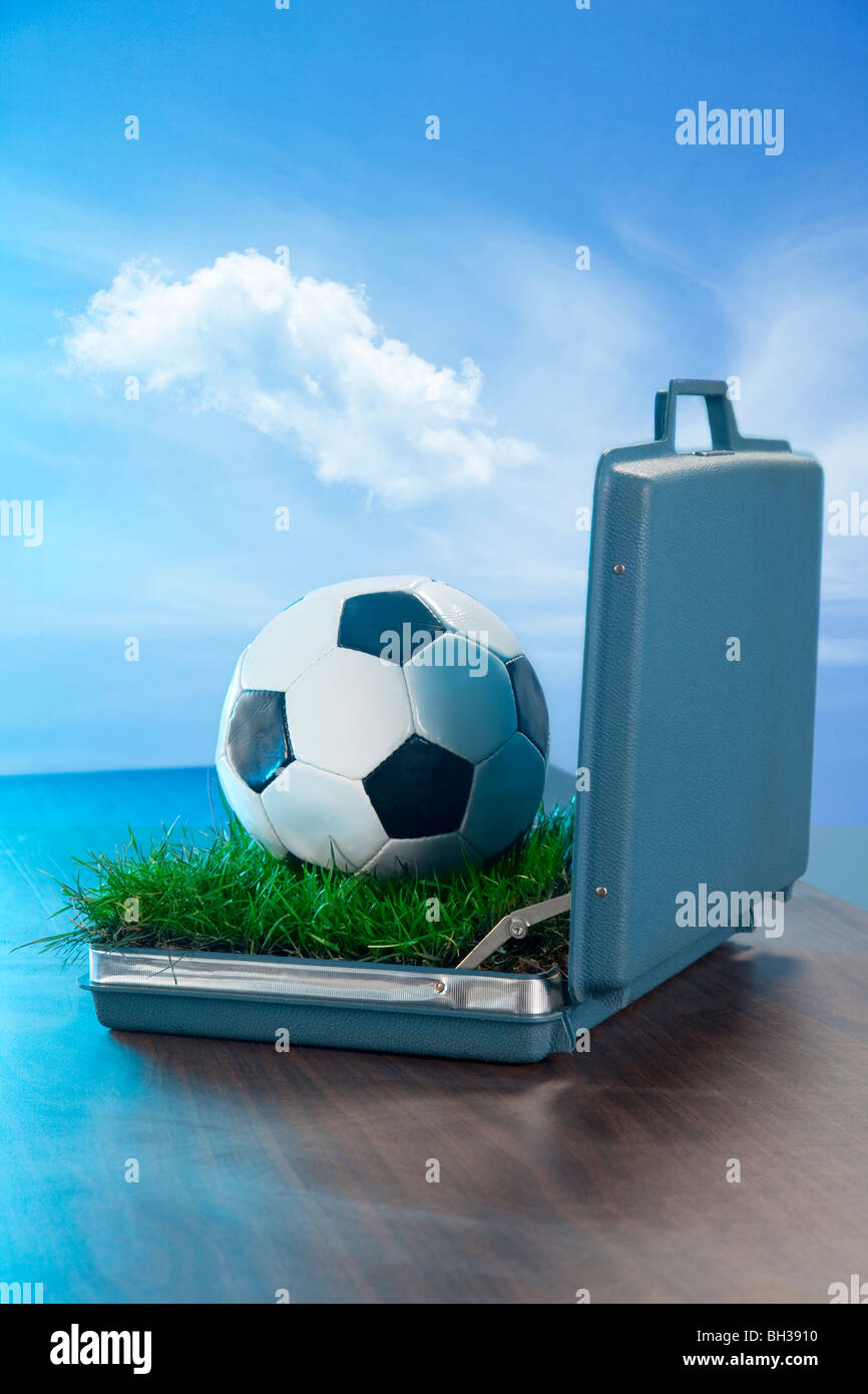 Valigetta aperta sulla scrivania con pallone da calcio in erba e all'interno Foto Stock