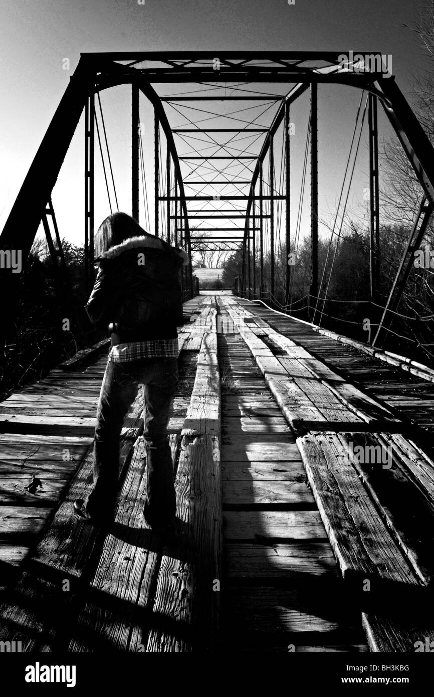 Signora meandro lungo un vecchio fatiscente antico ponte dal passato sembra essere scoraggiato su questa mattina il pupazzo di neve Foto Stock