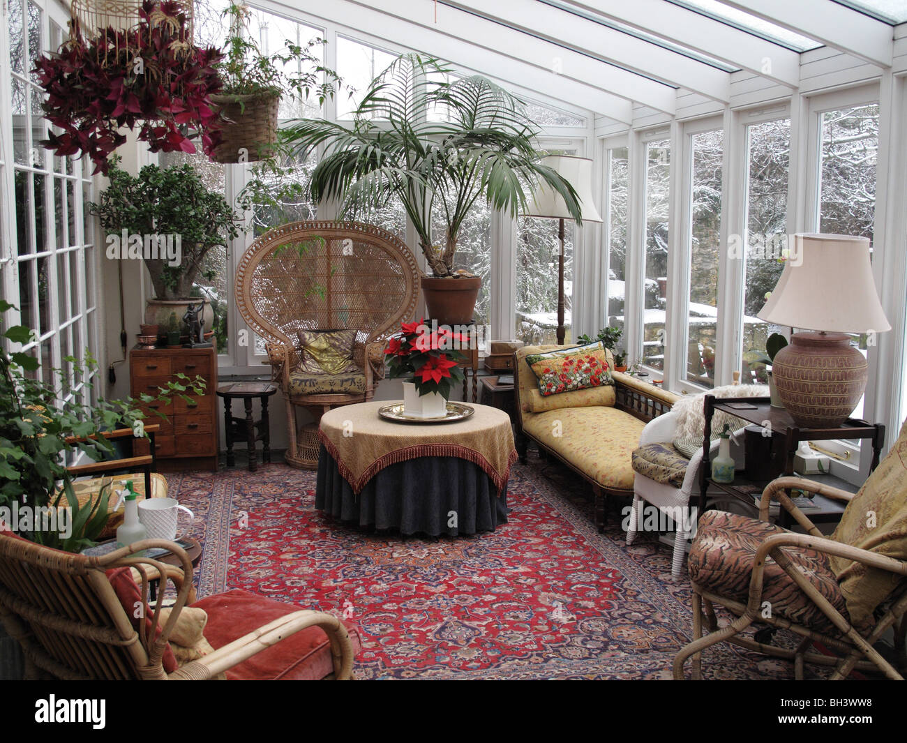Verniciato bianco conservatorio di legno duro con piante e mobili in metà inverno con neve al di fuori Foto Stock