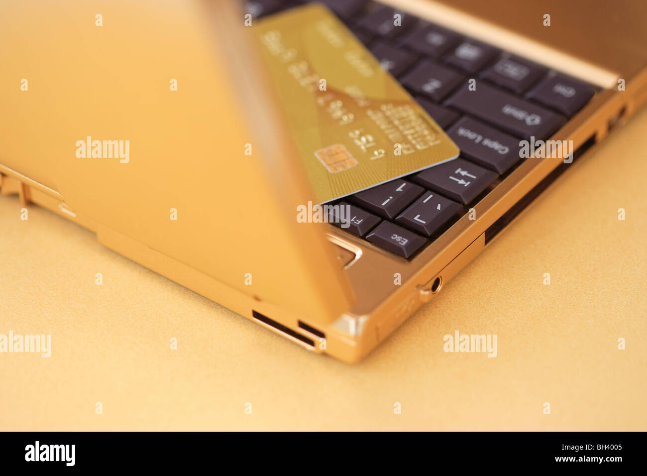 Un golden computer portatile e un golden carta di credito su un banco d'oro Foto Stock