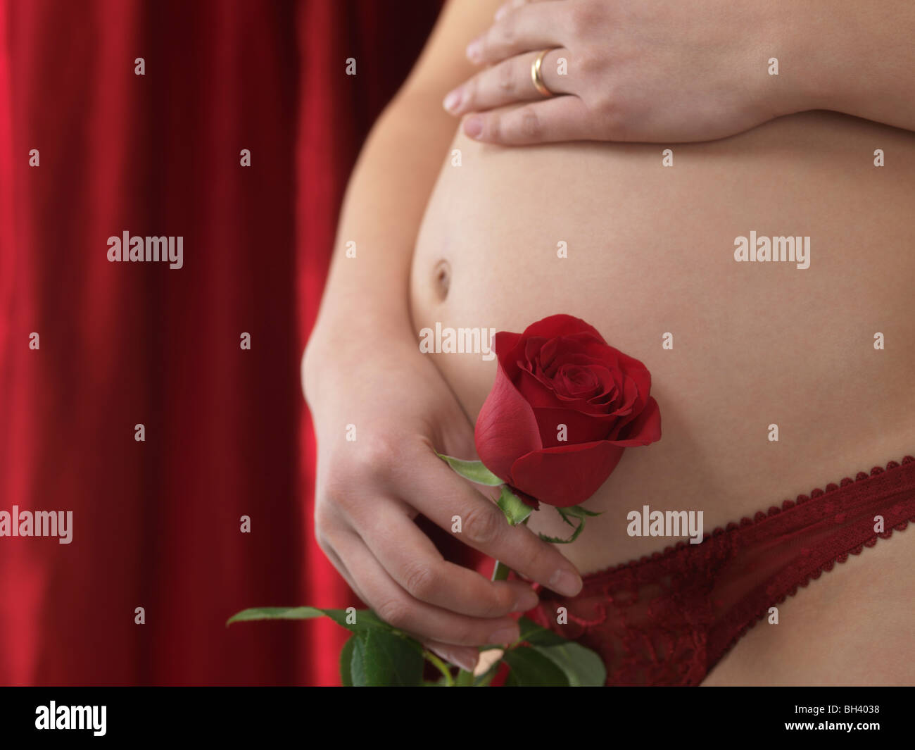 Donna incinta con una rosa rossa in mano Foto Stock