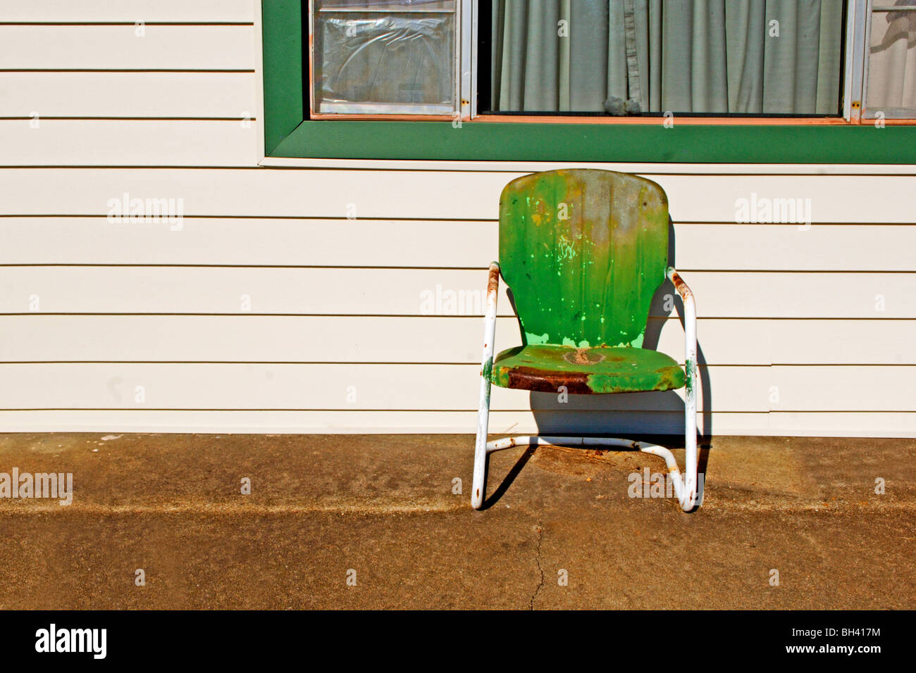 Vecchio usurato weathered sedia a partire dagli anni cinquanta si attende un pensionato finanziariamente solvente occupante per il riposo e il relax nel caldo sole Foto Stock
