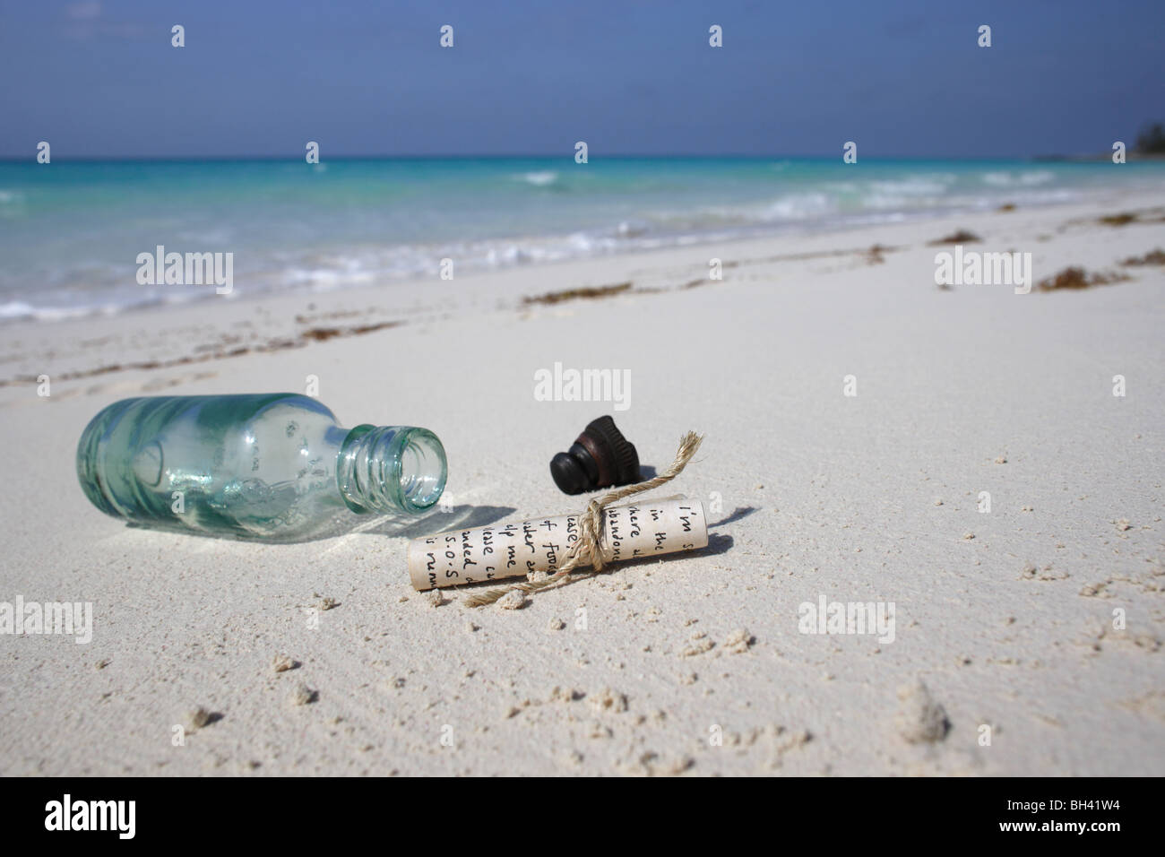 Un messaggio e una bottiglia sulla sabbia su una deserta spiaggia tropicale Foto Stock