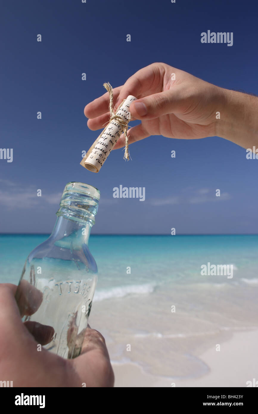 Un uomo con le mani in mano tenendo un messaggio in bottiglia su una deserta spiaggia tropicale Foto Stock