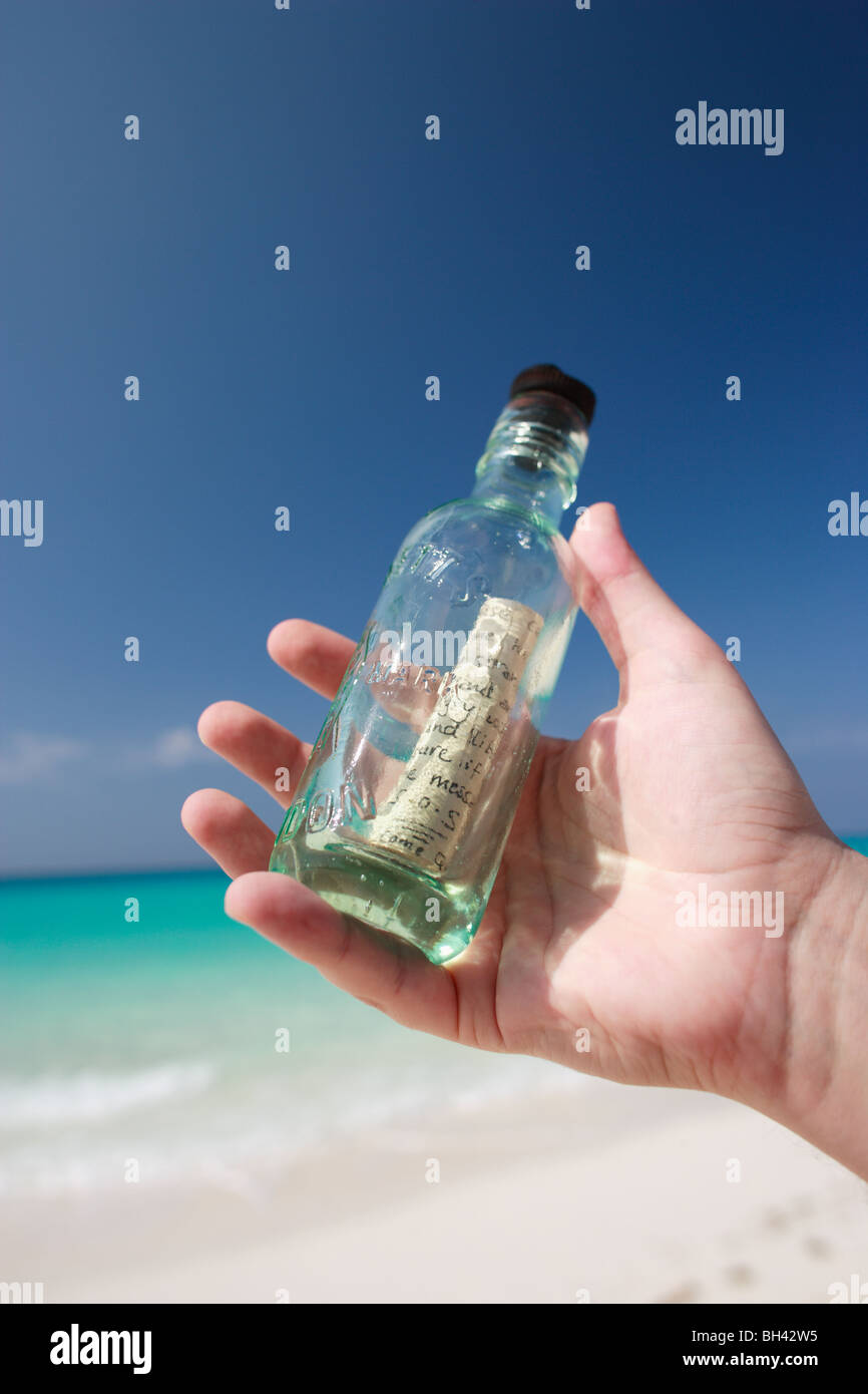 Un uomo con le mani in mano tenendo un messaggio in bottiglia su una deserta spiaggia tropicale Foto Stock