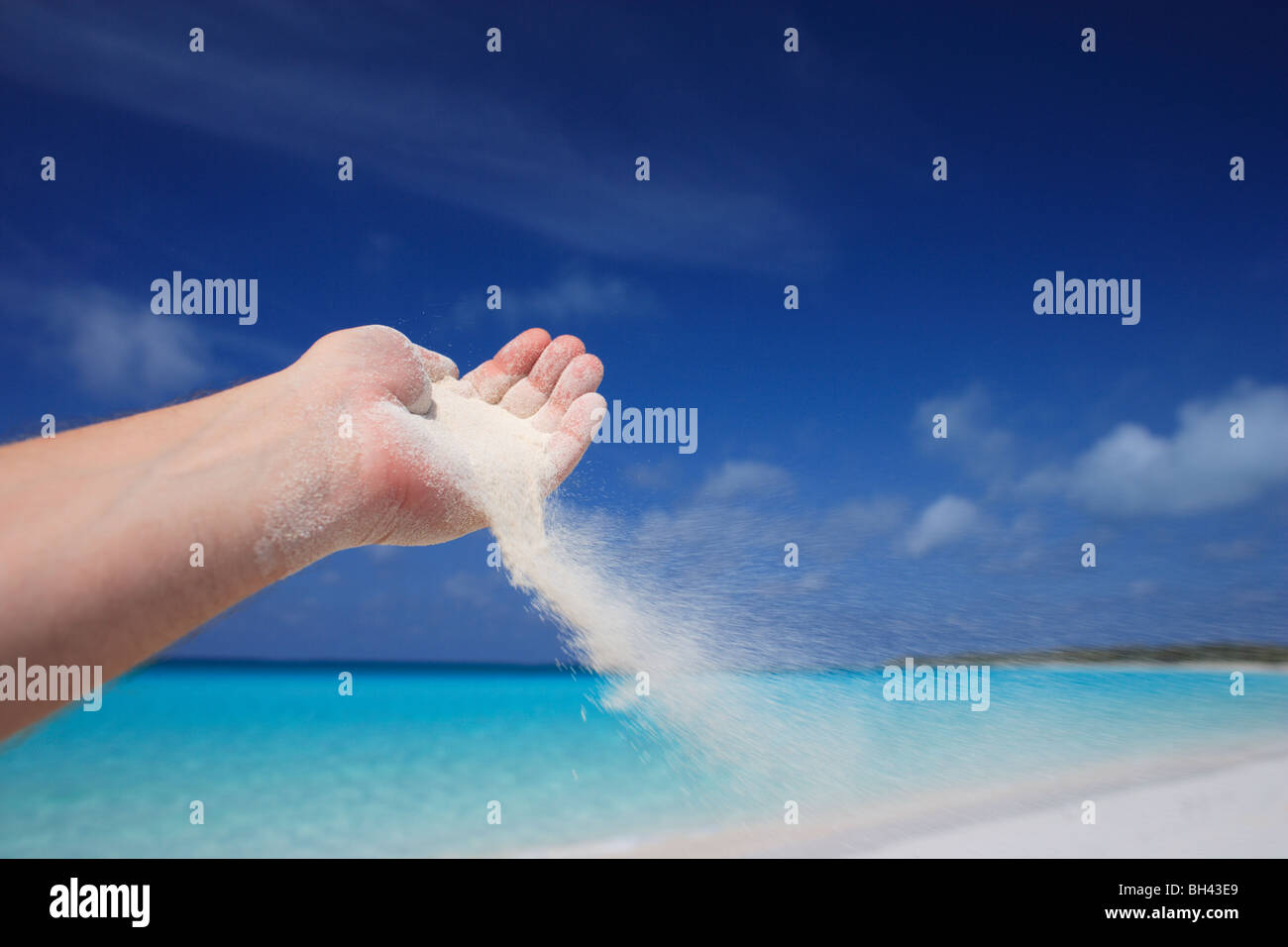 Una mano d'uomo sabbia versatore catturati nella brezza su una deserta spiaggia tropicale Foto Stock