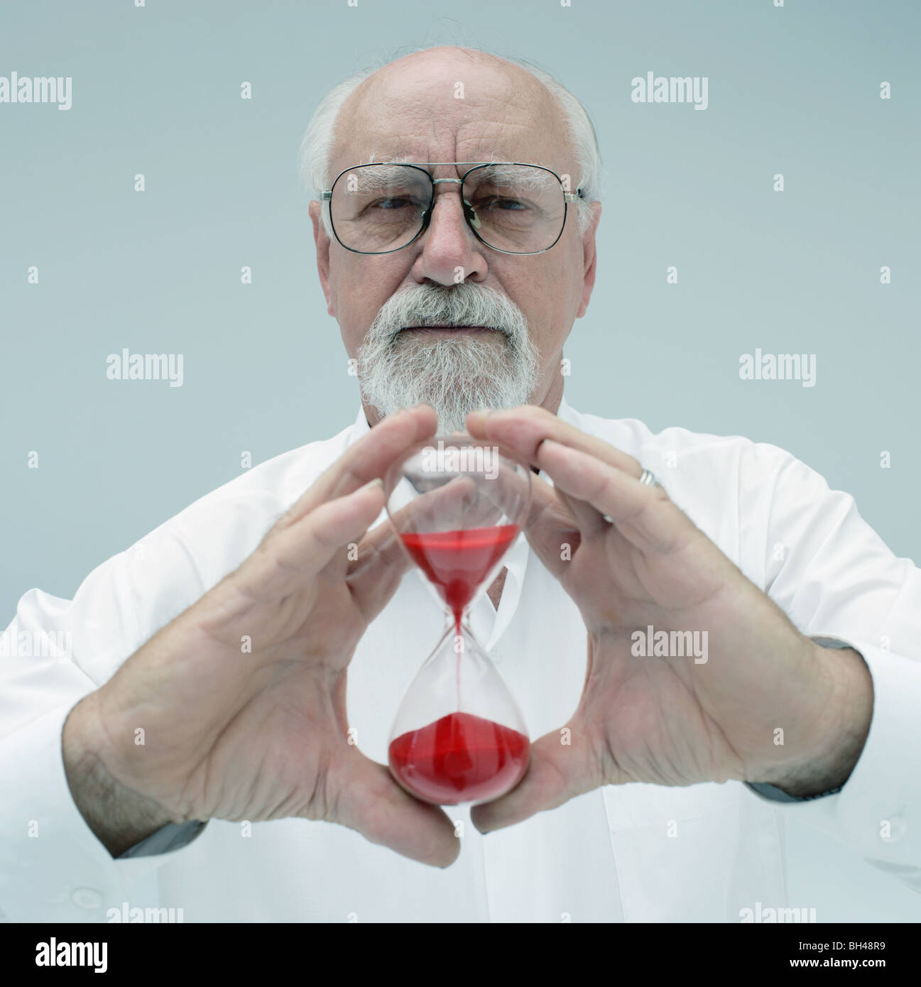 Un uomo anziano con in mano un bicchiere uovo timer con un espressione seria Foto Stock