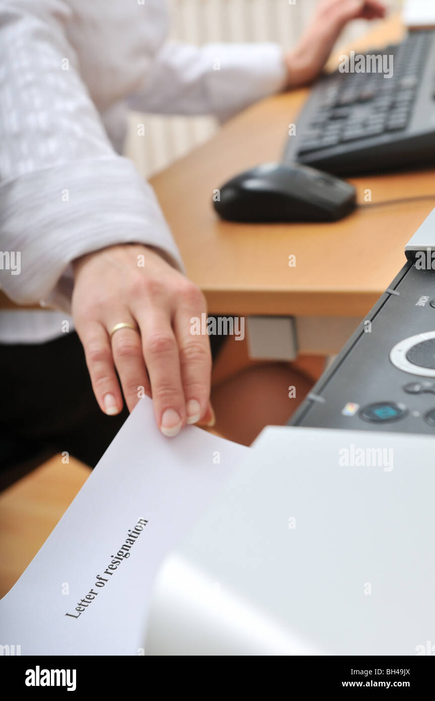 Mano di business donna reching carta (lettera di dimissioni scritta) dalla stampante sul posto di lavoro Foto Stock