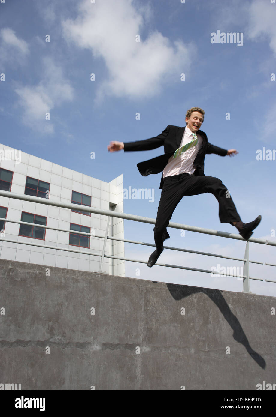 Giovane imprenditore saltando su una parete in città Foto Stock
