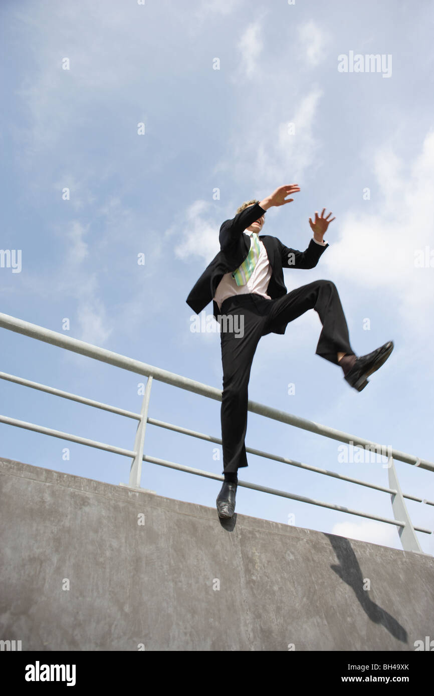 Giovane imprenditore saltando su una parete in città Foto Stock