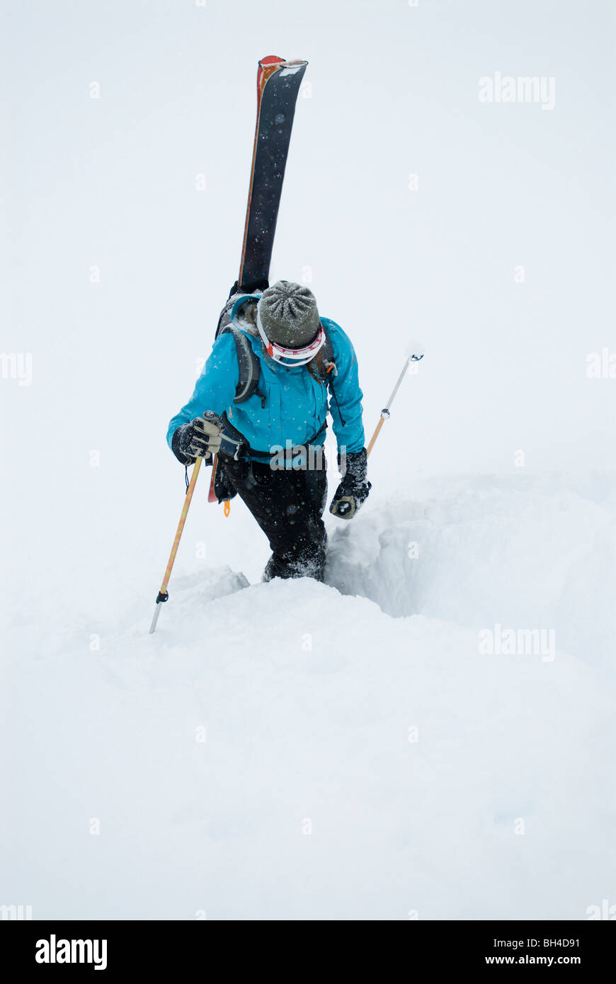 Una giovane donna confezioni i suoi sci e kick passaggi su un tratto di sentiero nel backcountry delle Canadian Rockies. Foto Stock