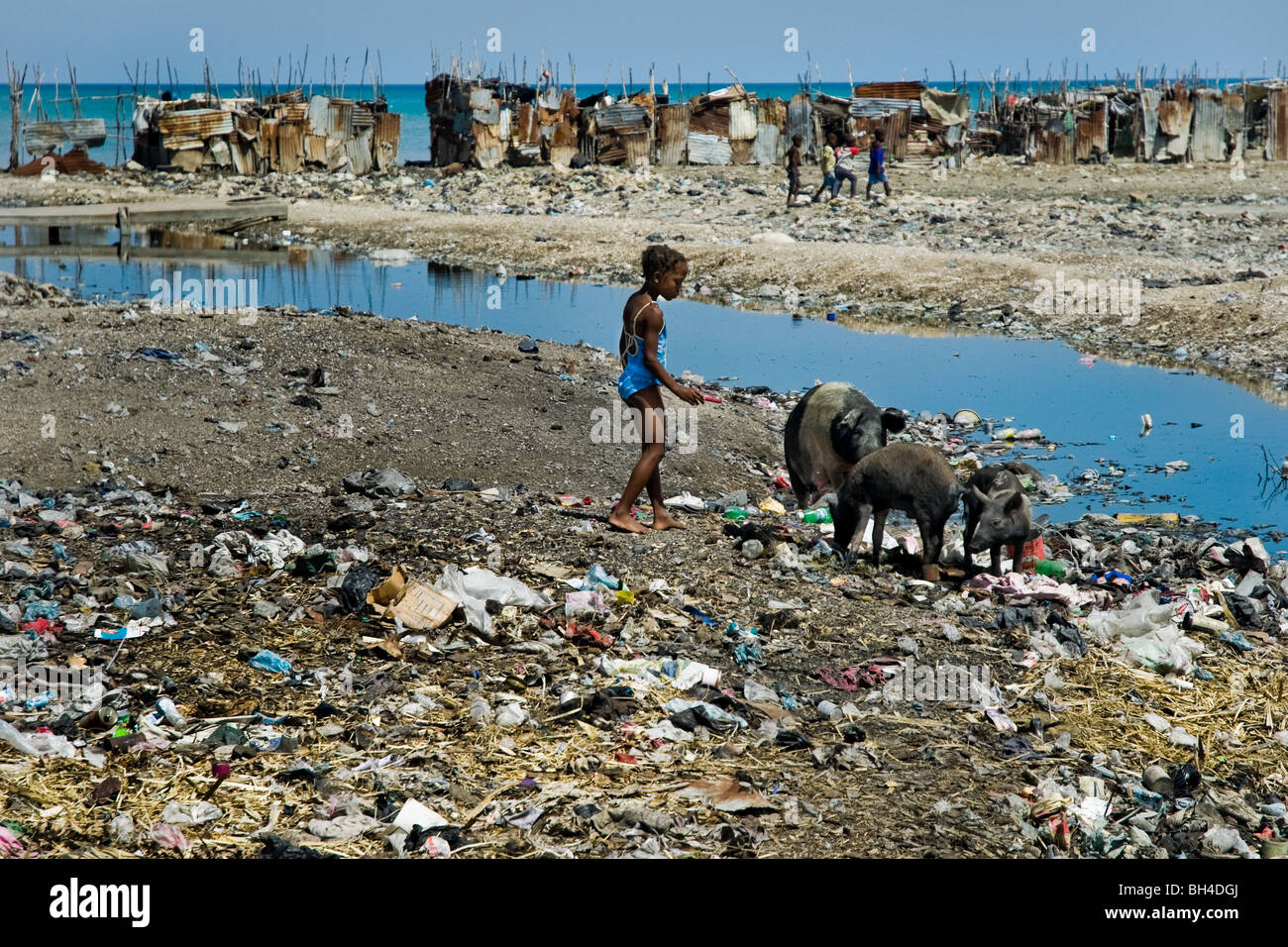 Una ragazza haitiana giocando in una discarica di rifiuti che circondano in baracche baraccopoli di cité soleil. Foto Stock