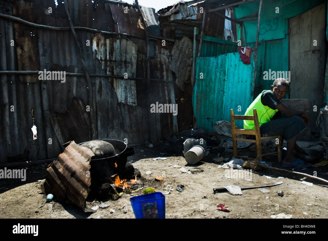 Un ragazzo haitiano nella preparazione degli alimenti sul fuoco nella baraccopoli di cité soleil. Foto Stock