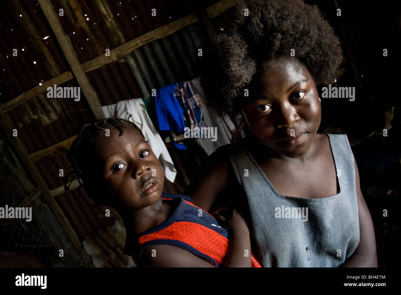 Una giovane madre haitiana tenendo il suo bambino dentro la baracca nella baraccopoli di cité soleil. Foto Stock