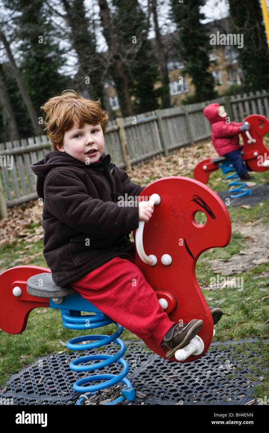 Bambini che giocano su un cavallo a dondolo in un parco giochi Foto Stock