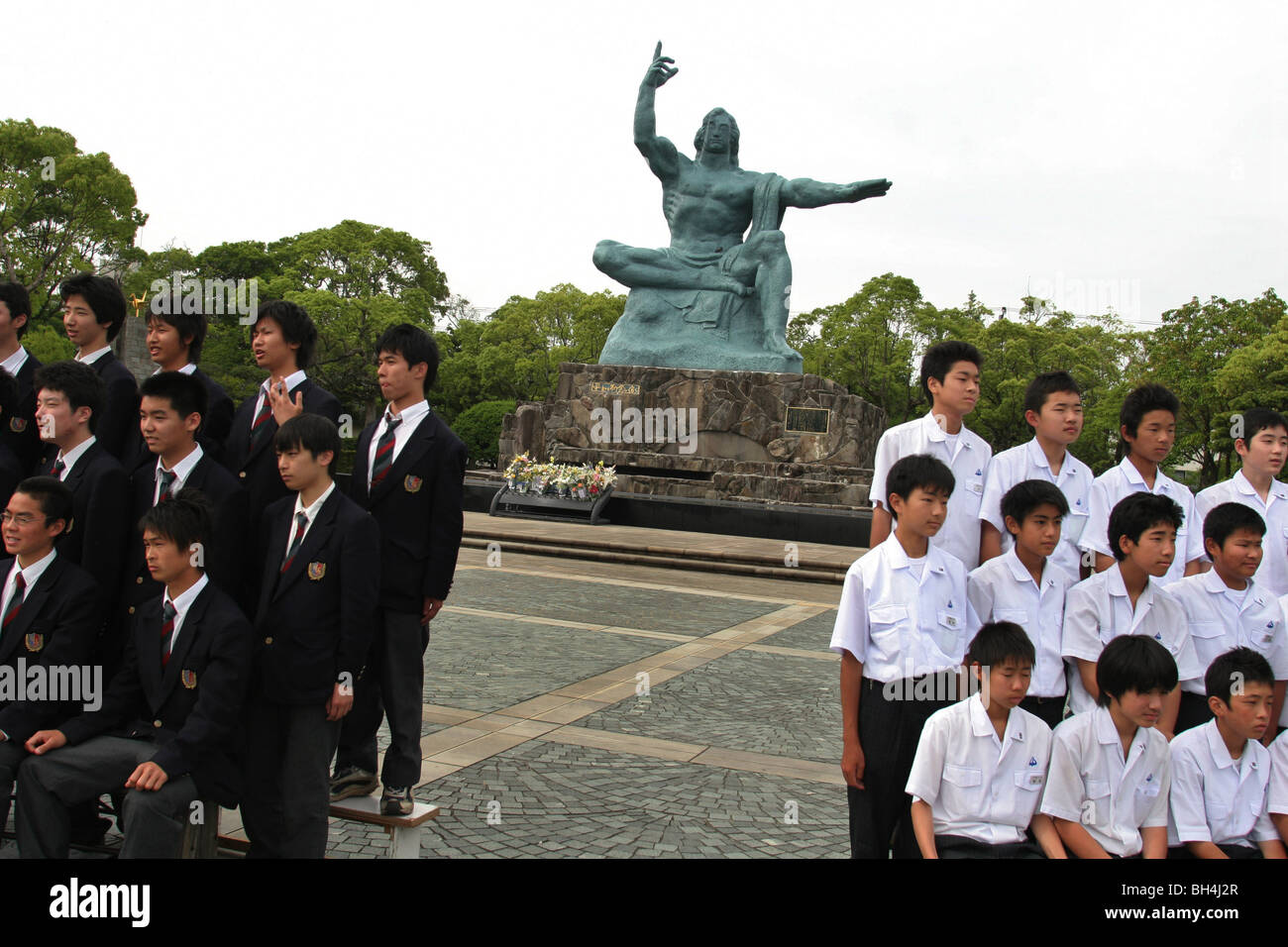 I bambini della scuola hanno le loro fotografie scattate nella parte anteriore del 1955 scultura di Seibo Kitamura in Nagasaki il Parco della Pace, Giappone Foto Stock