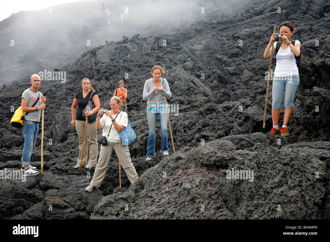 Viaggiatori sui flussi di lava attivi del vulcano Pacaya vicino a Antigua, Guatemala. La lave è così caldo è possibile sigarette leggere di esso Foto Stock