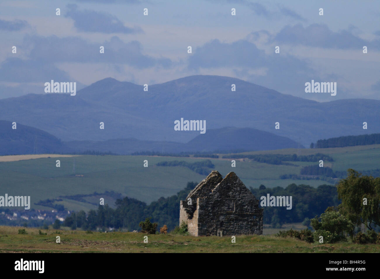 Abandonded cottage sul Cromarty Firth con campi e montagne sullo sfondo. Foto Stock