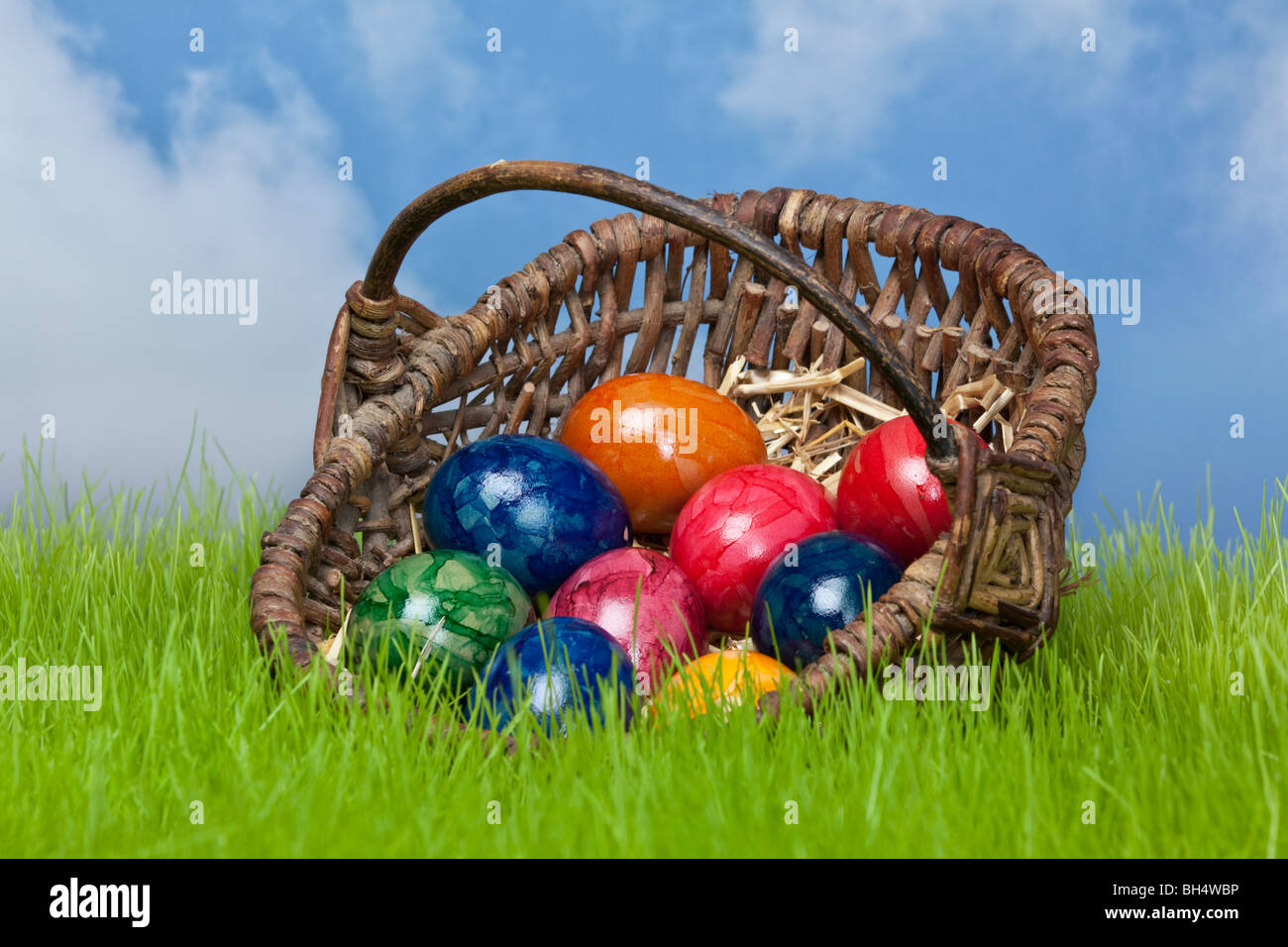 Uova di Pasqua in un cesto sui prati con il cielo in background Foto Stock