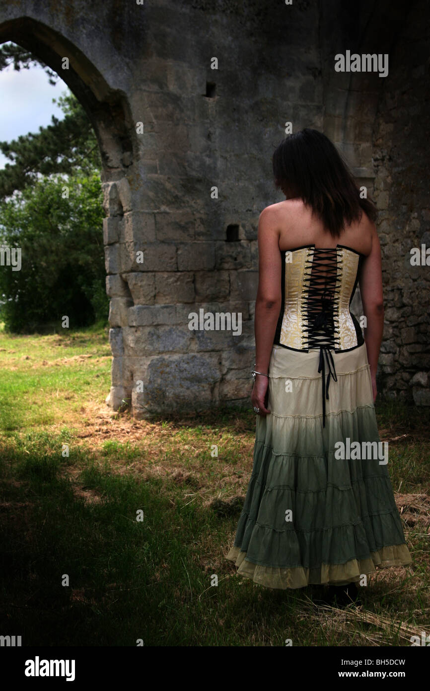 Signora indossando un 'chiocciola' Corsetto in rovine del Castello di Compiègne (Francia) foresta. Foto Stock