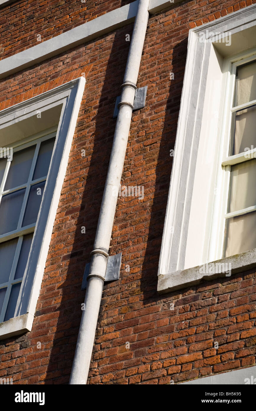 Un vecchio filo tubo di scarico / tubo verso il basso sulla parete di mattoni a Ham Casa nel Surrey. Foto Stock