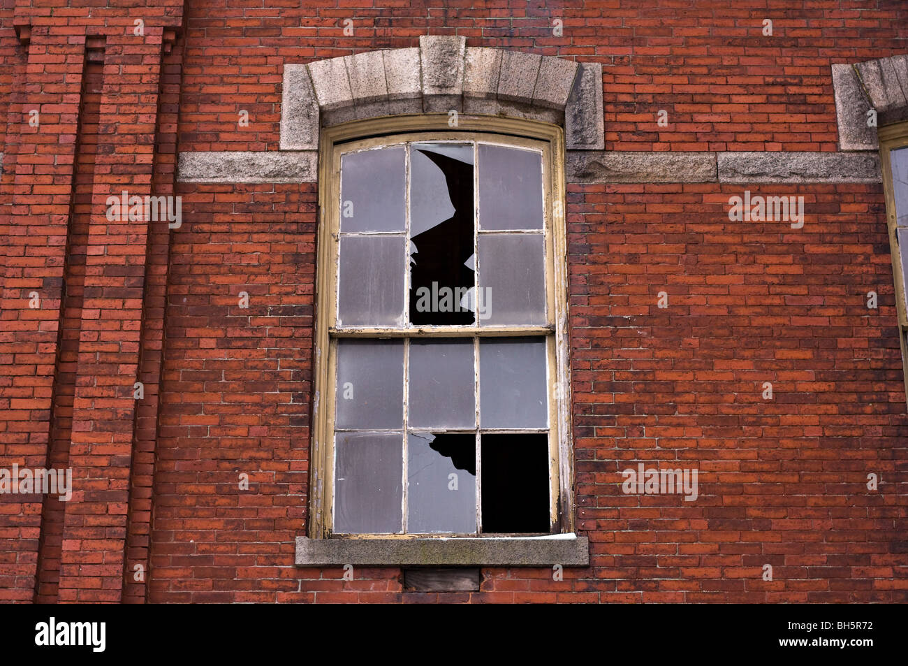 Edificio di mattoni con un vetro rotto. Foto Stock