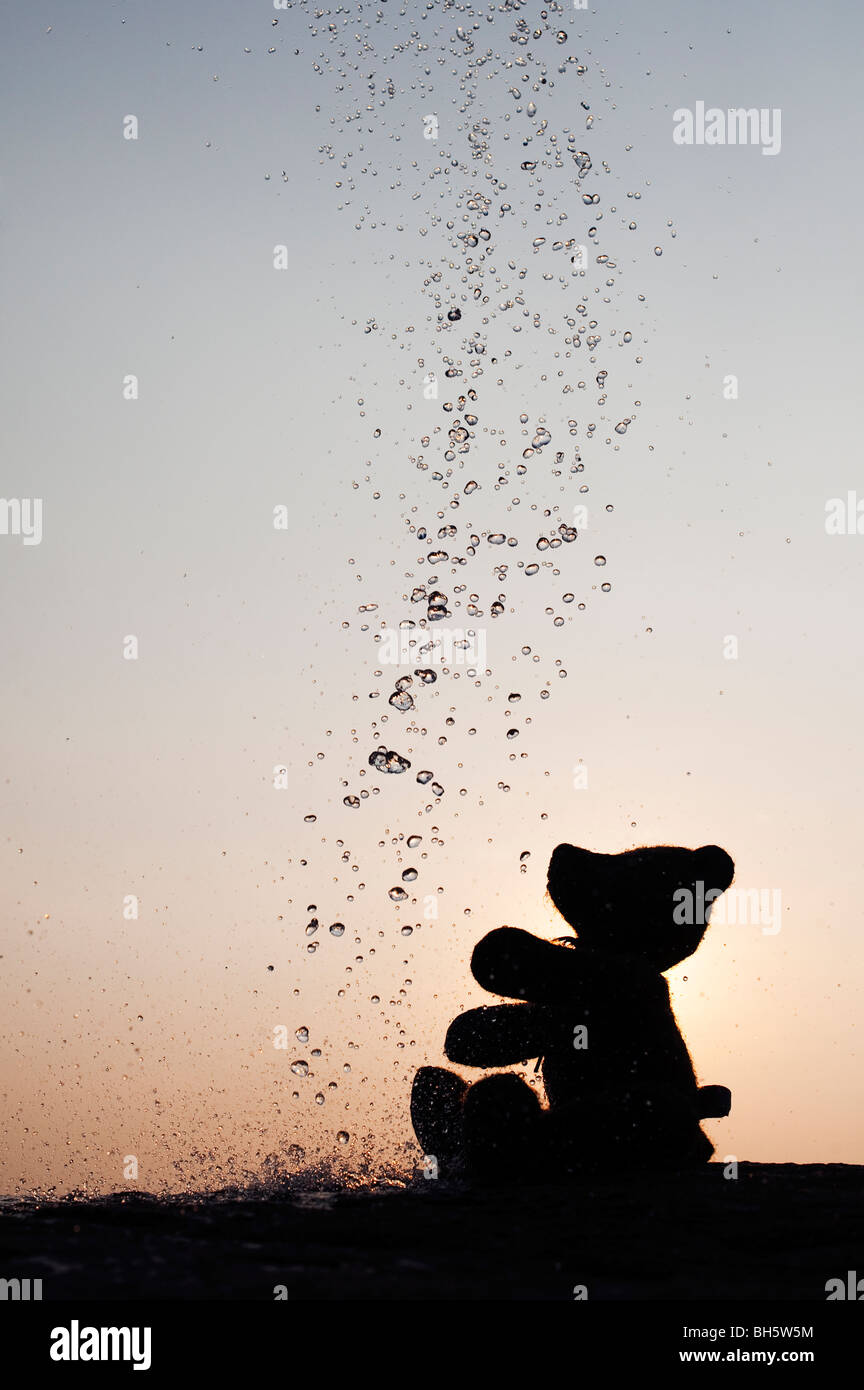 Orsacchiotto di peluche la cattura di gocce di acqua silhouette Foto Stock