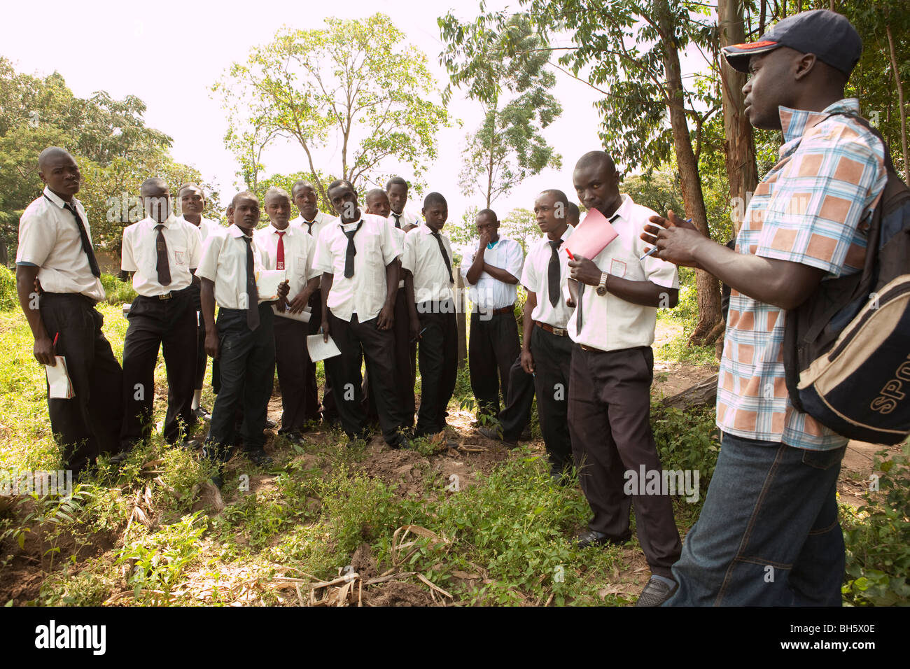 Gli studenti adolescenti imparare circa la conservazione dell'ambiente da tenere il ranger nel Kenya occidentale, vicino a Kakamega Forest Riserve. Foto Stock