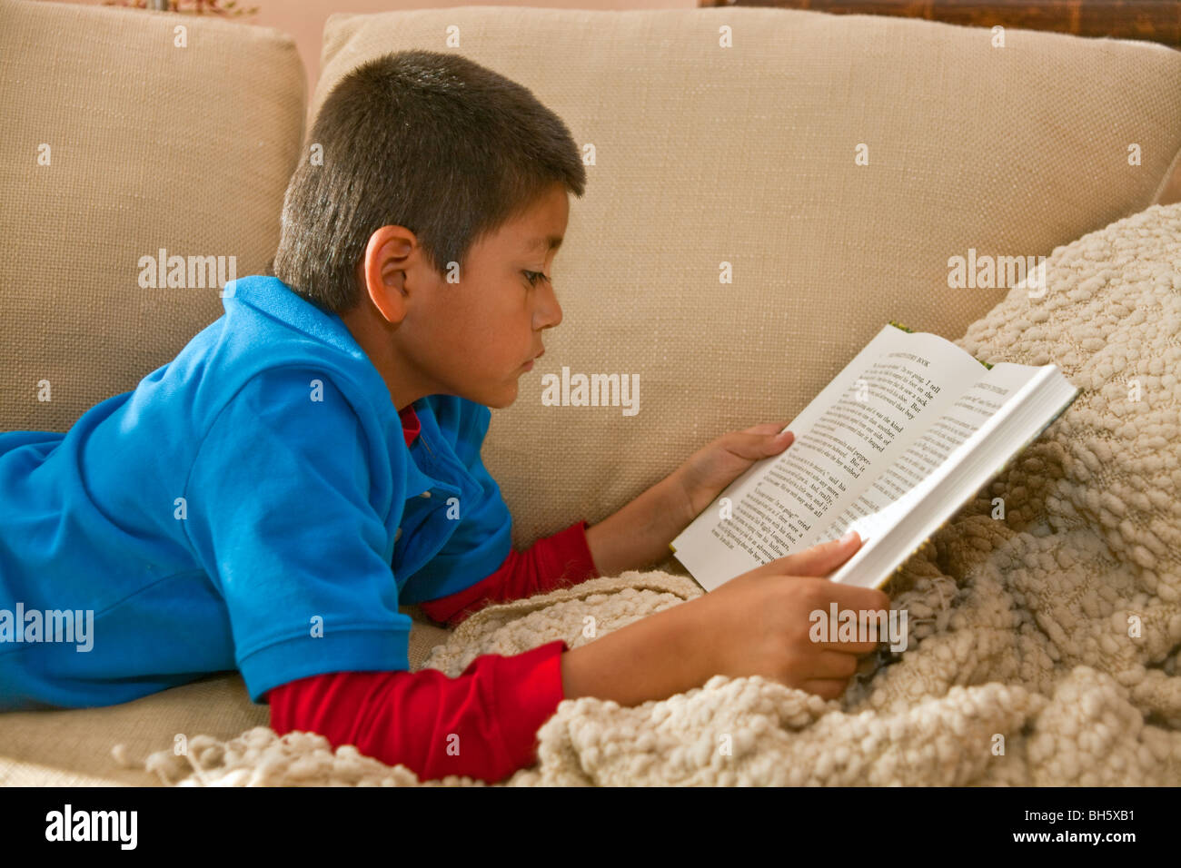 La lettura di un libro sul divano multi diversità razziale razziale multiculturale rilassa © Myrleen Pearson Foto Stock