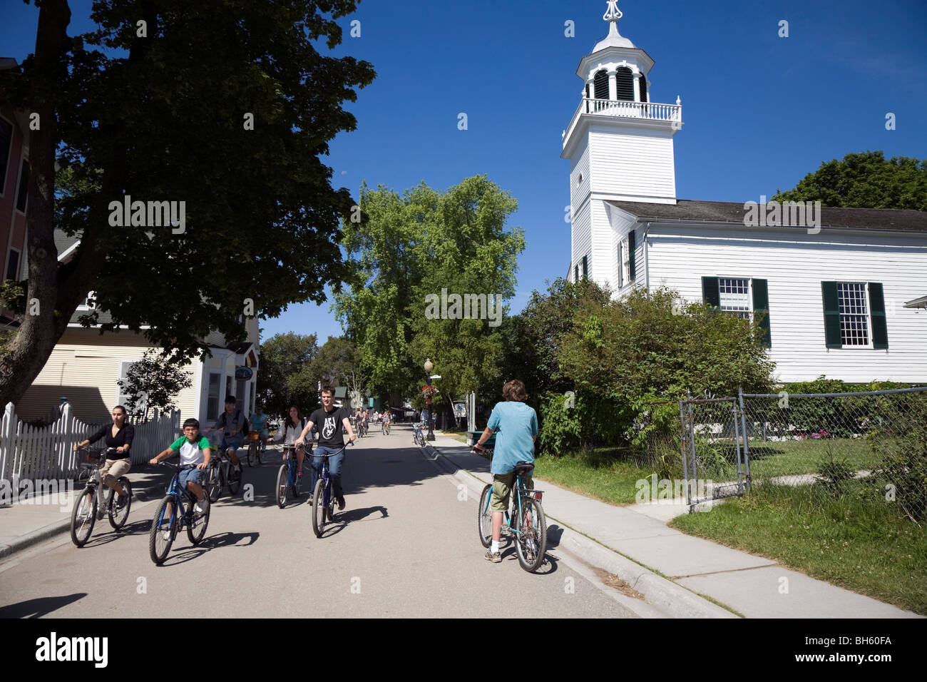 I turisti in bicicletta passato chiesa della missione sull isola di Mackinac, Michigan, Stati Uniti d'America. Foto Stock