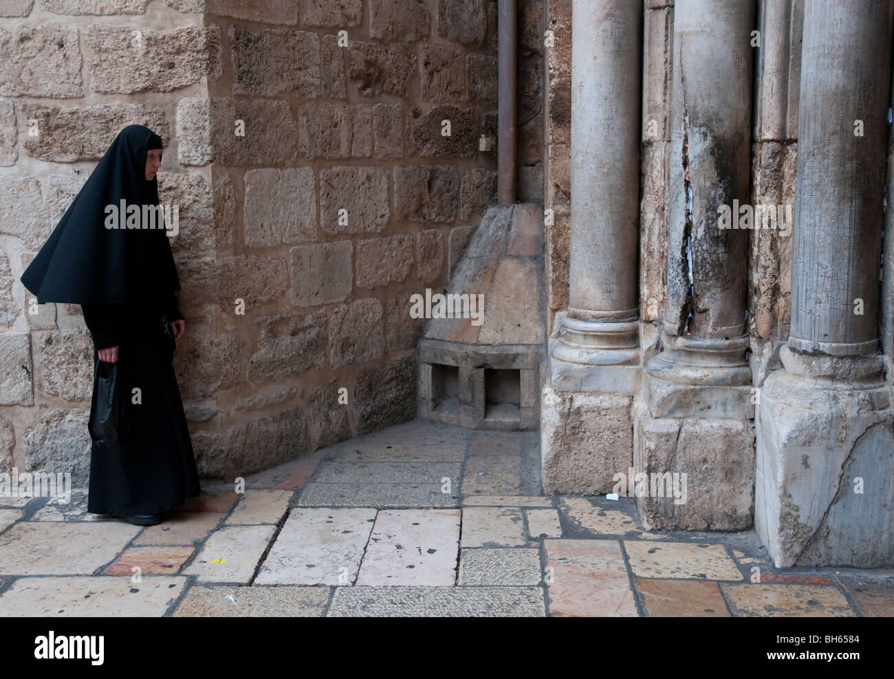 Suora ortodossa in piedi di fronte a colonne in ingresso al Santo Sepolcro Foto Stock