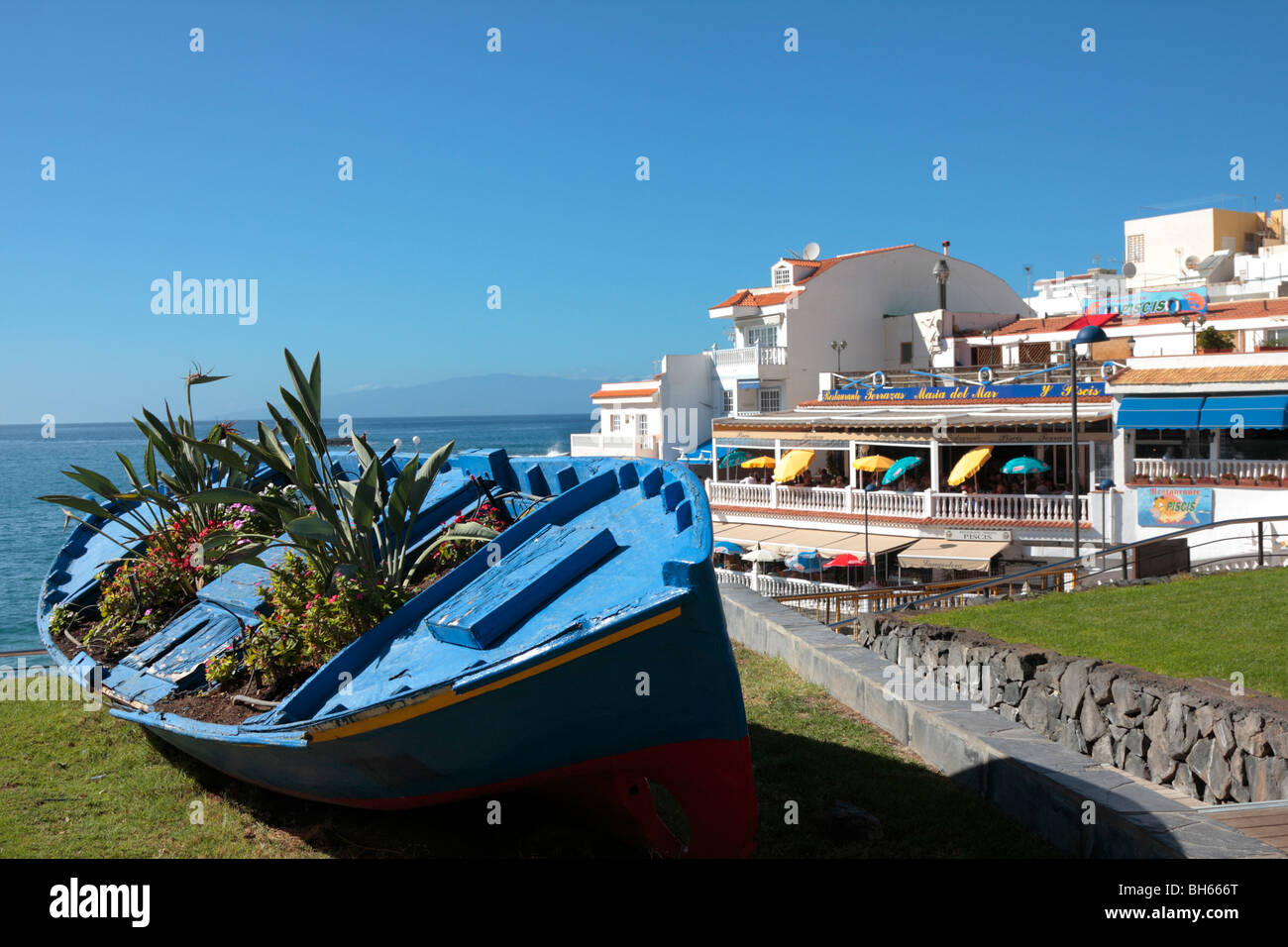 Una vecchia barca da pesca si arricchisce di una nuova vita come un vaso di fiori su un prato dai ristoranti di La Caleta sulla costa occidentale di Tenerife Foto Stock